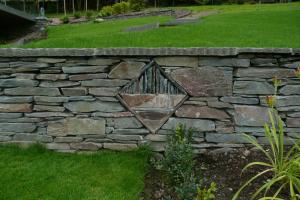 A sculpture built within a stone wall using local elterwater slate