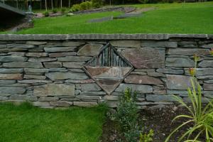 A sculpture built within a stone wall using local elterwater slate